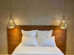 a bed with white pillows and two lights above it at Mineral Stone- T2 Standing in Cayenne