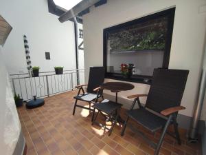 d'un balcon avec des chaises, une table et une fenêtre. dans l'établissement Ferienwohnung 'Unter der Burg', à Brodenbach