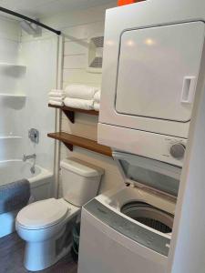 a small bathroom with a toilet and a washing machine at Sunrise Loft - Beach front guest house in Sandspit