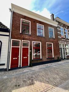 um edifício de tijolos com portas vermelhas numa rua em Pandje 118 - Binnenstad Kampen em Kampen