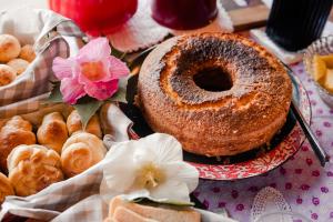 una mesa con un pastel y varios pasteles y flores en Pousada Morada Dos Anjos, en Arroio do Meio