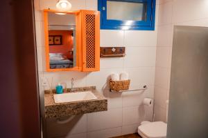 a bathroom with a sink and a mirror and a toilet at Pousada Morada Dos Anjos in Arroio do Meio