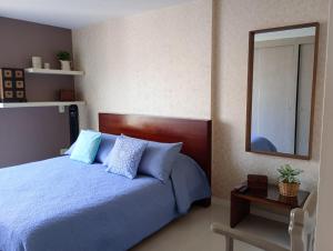 ein Schlafzimmer mit einem blauen Bett und einem Spiegel in der Unterkunft Ubicación privilegiada. Todo al alcance de tu mano in Sabaneta