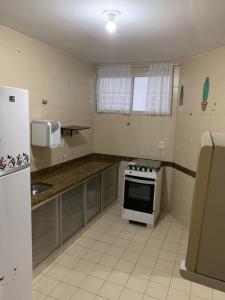 a small kitchen with a stove and a refrigerator at APARTAMENTO PRAIA DO MORRO, 04 QUARTOS, ATE 10 PESSOAS. in Guarapari