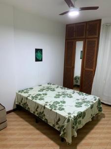 1 dormitorio con 1 cama con manta verde en APARTAMENTO PRAIA DO MORRO, 04 QUARTOS, ATE 10 PESSOAS., en Guarapari