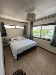 a bedroom with a large bed and two windows at Beach side Duplex in Punaauia