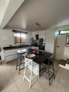 uma cozinha com uma mesa preta e cadeiras num quarto em Beach side Duplex em Punaauia