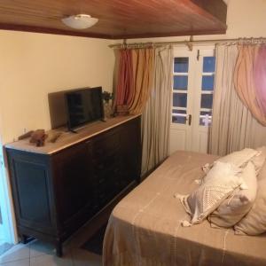 a bedroom with a bed and a tv on a dresser at Chalé Pé da Serra in Penedo