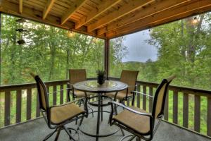 eine abgeschirmte Veranda mit einem Tisch und Stühlen in der Unterkunft ENJOY & have some FUN! Cabin with Game Room & Hot Tub in Blue Ridge