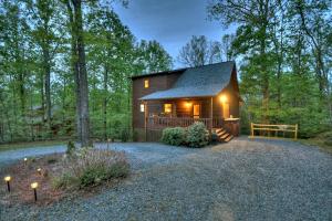 a small log cabin in the woods with lights on at ESCAPE & ENJOY HAVEN - Cabin with Game Room & Hot Tub in Blue Ridge