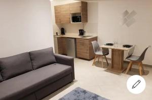 a living room with a couch and a table and a kitchen at STUDIOS NEUFS ET AGRÉABLES in Bonneuil-sur-Marne