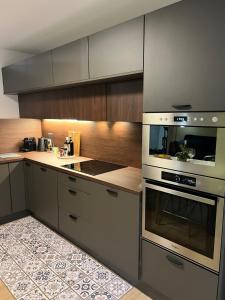 a kitchen with stainless steel appliances and wooden cabinets at Le K Appartement - Strasbourg in Strasbourg