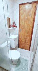 a bathroom with a toilet and a wooden door at Apartamento Econômico na Gilka Machado in Rio de Janeiro