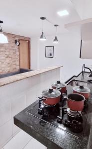 a kitchen with four pots and pans on a stove at Apartamento Econômico na Gilka Machado in Rio de Janeiro