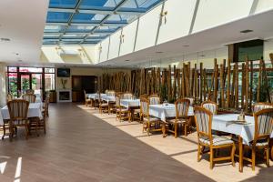 un comedor con mesas blancas y sillas de madera en Хотел "Скалите", Skalite Hotel en Belogradchik