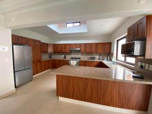 a kitchen with wooden cabinets and a stainless steel refrigerator at Villa acogedora con patio estilo hacienda. in Ajijic