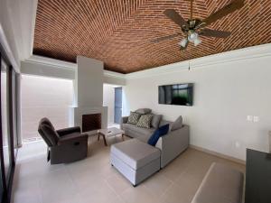 sala de estar con ventilador de techo, sofá y silla en Villa acogedora con patio estilo hacienda., en Ajijic