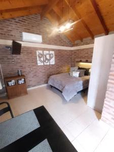 Un dormitorio con una cama grande y una pared de ladrillo. en Cabaña Los ALAMOS, en Los Reartes