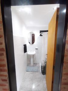 baño con lavabo y aseo con espejo en Cabaña Los ALAMOS, en Los Reartes 7 fotos más