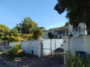 a white fence in front of a white house at R reasonable Air BNB. in Montego Bay