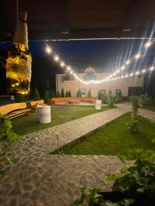 a patio at night with a bottle of beer and lights at Pensiunea Perla Râușor in Rîuşor