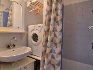 Un baño con lavabo y lavadora. en Charmant studio avec terrasse et parking couvert - FR-1-505-49, en Notre-Dame-de-Bellecombe