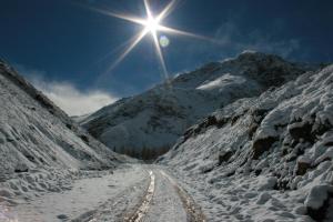 a sun shines over a snow covered mountain road at Hostal Crisol in Lo Valdés