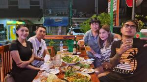 Un groupe de personnes assises autour d'une table et mangeant de la nourriture dans l'établissement Rainbow Hotel Vientiane, à Vientiane