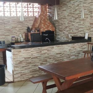 cocina con mesa de madera y pared de ladrillo en Sobrado lindo, en Campo Grande