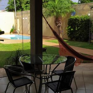 un patio con una mesa de cristal, sillas y una hamaca en Sobrado lindo, en Campo Grande