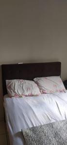 Una cama con dos almohadas encima. en Sobrado lindo, en Campo Grande