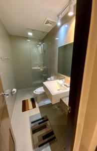 Classy 2BR Suite at Eastwood City with Pool and City Skyline View في مانيلا: حمام مع حوض ومرحاض ومرآة
