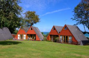 two houses with red roofs on a green lawn at Escape to a Clifftop Chalet with pool and tennis onsite - 1A Kingsdown Holiday Park in Kingsdown