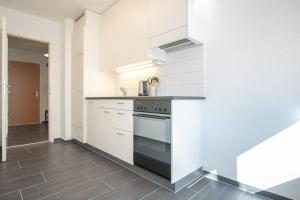 Modern 2-Bedroom Apartment in City Centre في بازل: مطبخ بدولاب بيضاء وموقد