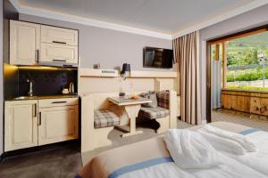 Cette chambre comprend un lit, un bureau et une cuisine. dans l'établissement MONDI Hotel Tscherms, à Cermes