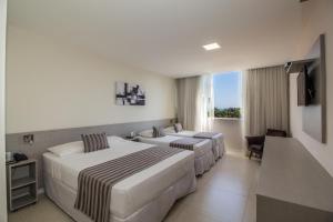 a hotel room with two beds and a television at Pousada Molinha in Penha