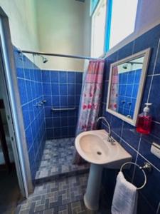 a blue tiled bathroom with a sink and a shower at El Arrecife Martin Pescador in Taxisco