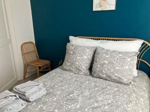a bed with two pillows and a blue wall at Joli appartement à Brive la gaillarde in Brive-la-Gaillarde