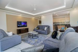a living room with two couches and a tv at Sedra home@Aqua apartments in Mombasa
