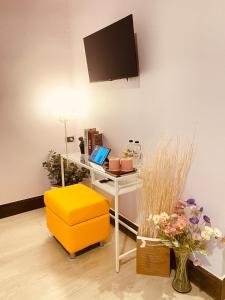 um quarto com uma secretária com um computador portátil e um banco amarelo em Triple J hotel Trang em Trang