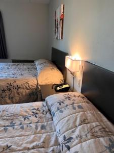 a room with two beds and a lamp and a laptop at Kirkfield Motor Hotel in Winnipeg