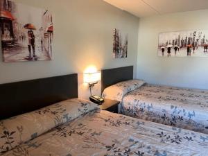 a hotel room with two beds and paintings on the wall at Kirkfield Motor Hotel in Winnipeg