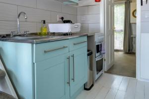a kitchen with blue cabinets and a sink at Escape to a Clifftop Chalet with pool and tennis onsite - 38 Kingsdown Park in Kingsdown