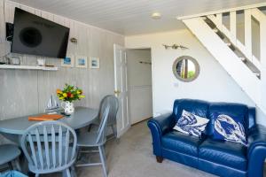 a living room with a blue couch and a table at Escape to a Clifftop Chalet with pool and tennis onsite - 38 Kingsdown Park in Kingsdown