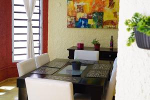 a dining room table with white chairs and a painting at Casa Avocado, en García Gineres in Mérida