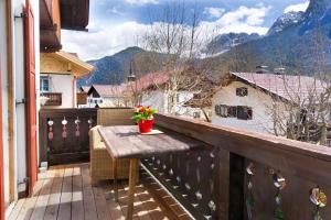 a wooden balcony with a table and flowers on it at Peter - a87525 in Mittenwald