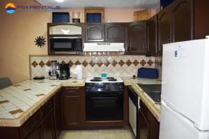 a kitchen with wooden cabinets and a black stove top oven at Marina Pinacate A-520 in Puerto Peñasco