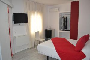 a bedroom with a red and white bed and a tv at Hostal Madrid Sol in Madrid