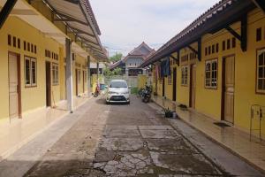 un coche aparcado en una calle con edificios amarillos en SPOT ON 93005 Berkah Kedawung Syariah en Cirebon