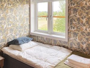 1 cama con ventana en una habitación con papel pintado en Holiday home HJORTKVARN III en Haddebo